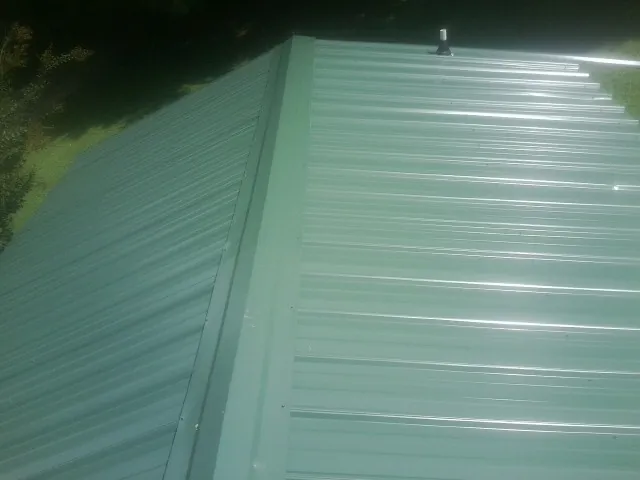 New green metal panels meeting at the ridge of a roof — Flat Roof Repair work by our crew in Jasonville