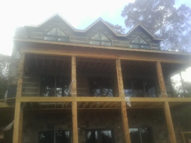 Dormers and porch framing on a large log home under construction — Roof Coating work by our crew in Jasonville