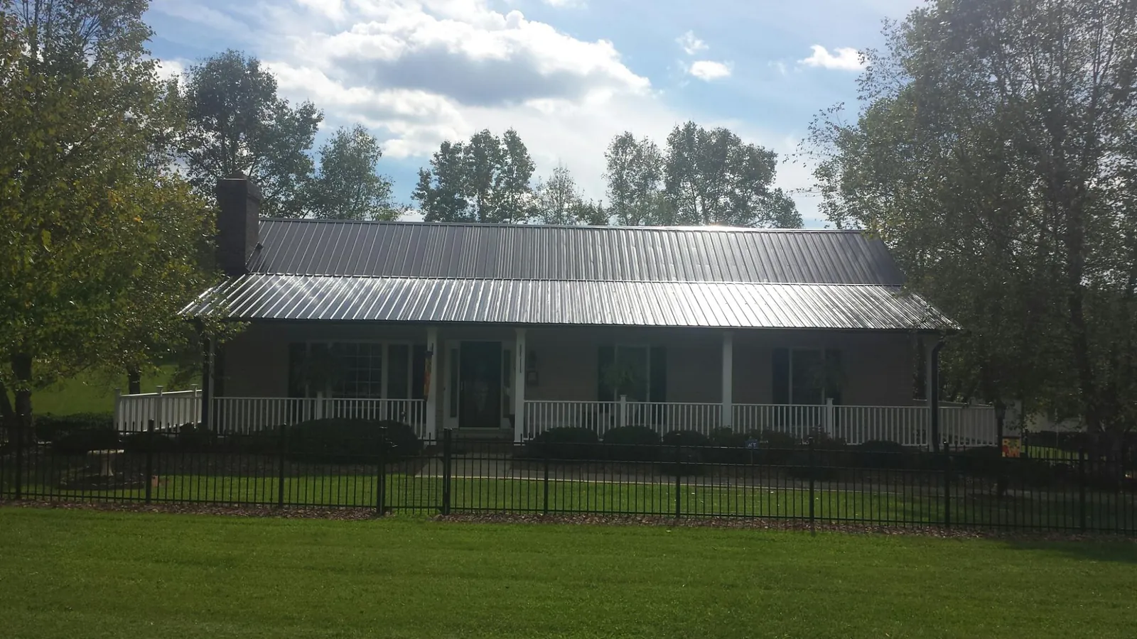 Gray metal roof on a brick ranch with a full width front porch — Gutter Guard Installation work by our crew in Jasonville