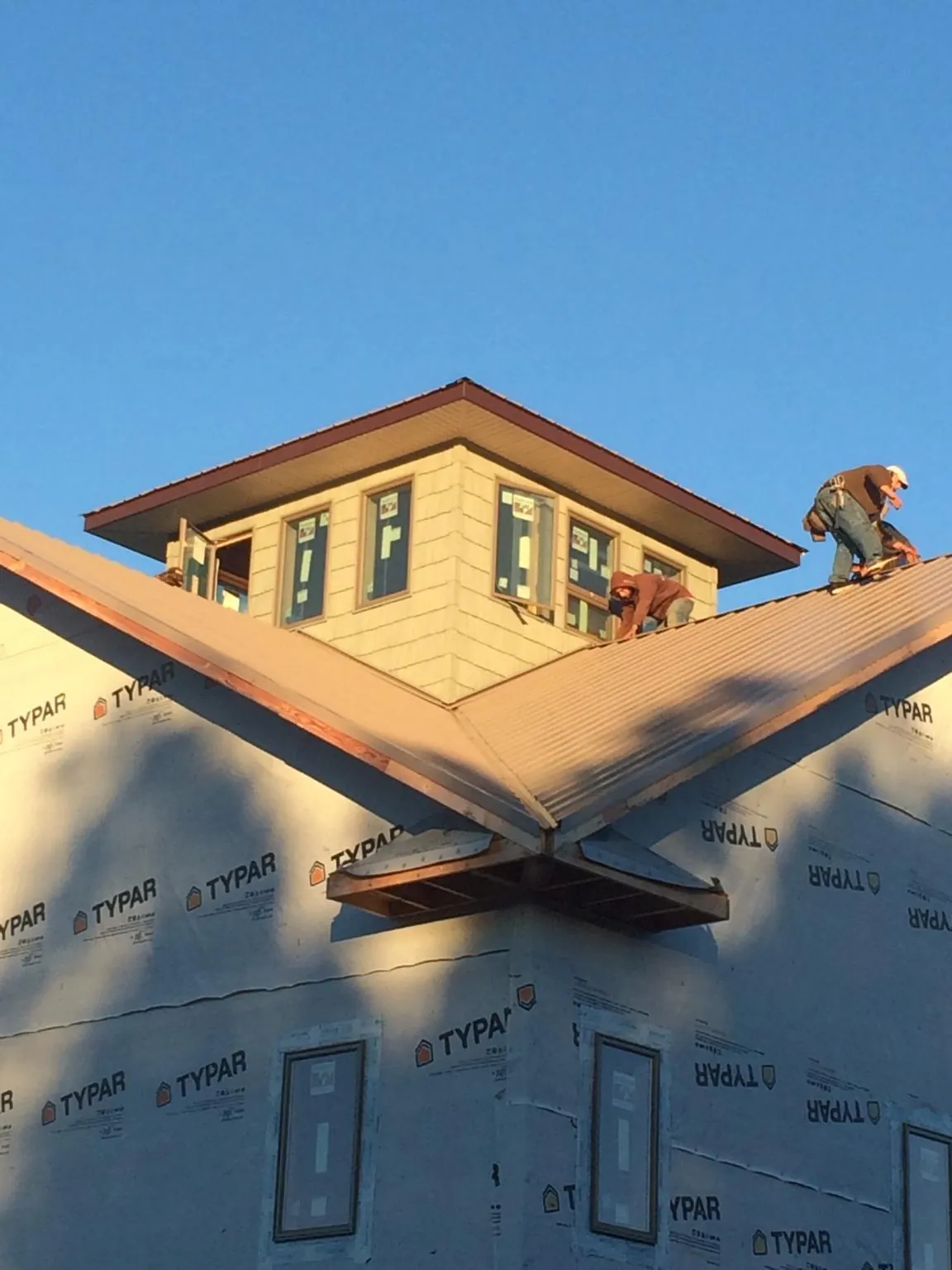 Roofers working around a rooftop cupola on a new metal roof at sunset — Roof Waterproofing in Jasonville by Roofing Brothers